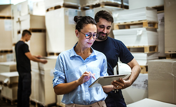 Warehouse supervisor holding tablet talking to warehouse manager