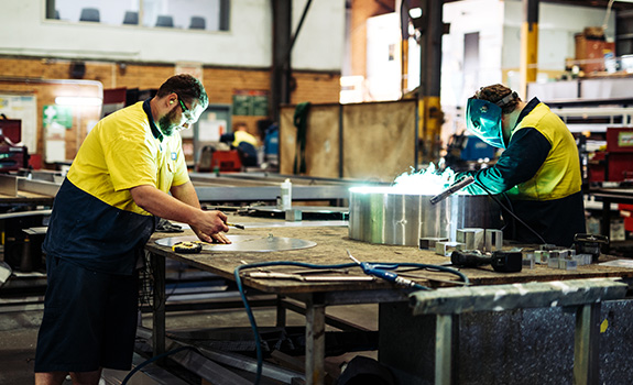 Two workers manufacturering steel components in factory